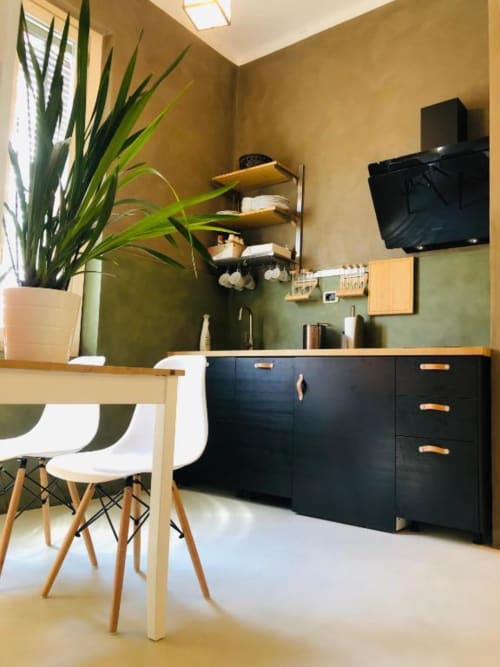 Camera matrimoniale moderna a Casa Città B&B a Brescia con mobili neri, scrivania in legno naturale, pianta in vaso e TV a parete.