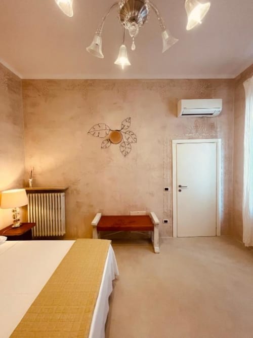 Deluxe Triple Room presso Casa Città Brescia con letto, panchetta, decorazioni murali ornamentali, plafoniera, aria condizionata e porta bianca