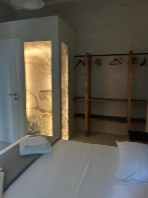 Camera moderna di Casa Città Brescia B&B con armadio illuminato, attaccapanni in legno e biancheria bianca