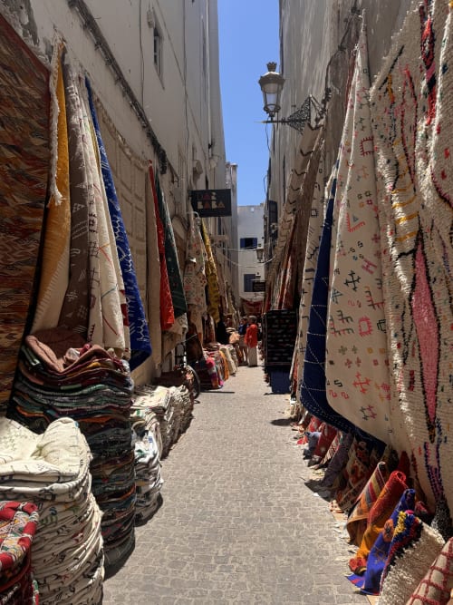 Tapis et textiles tissés à la main aux couleurs vives exposés dans une ruelle étroite du marché d'Essaouira