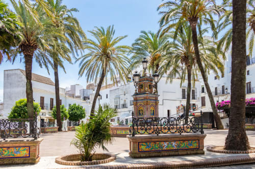 Plaza encantadora de Casa De La Cruz Vejer con palmeras, kiosco decorativo, edificios blancos y azulejos coloridos en Vejer