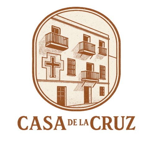 Logotipo Casa De La Cruz Vejer con fachada colonial, cruz y balcones en tonos marrones