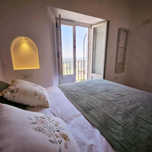 Luminosa habitación en Casa De La Cruz Vejer con cama doble, luz amarilla, puertas abiertas al balcón y vistas a las montañas