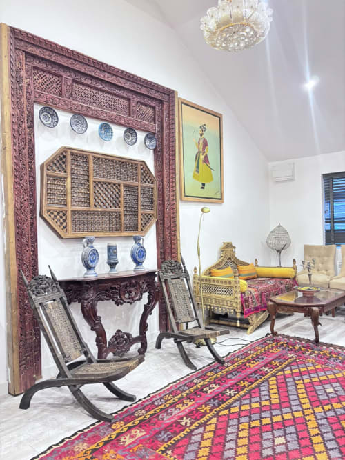 Elegant furnished bedroom with ornate carved wooden frame, blue porcelain plates, decorative bed with gold accents, and