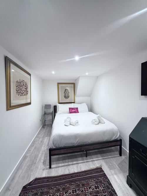 Modern bedroom at England Furnished Homes in High Wycombe with white bedding, Islamic wall art, and contemporary furnishings