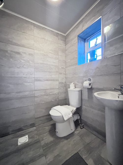 Modern gray tiled bathroom in England Furnished Homes, High Wycombe with toilet, sink, and window