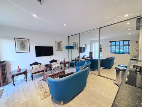 Modern 2BR annex in High Wycombe with blue chairs, kitchen, and mirrored living space