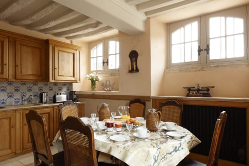 Salle à manger rustique du Château de Servigny avec meubles en bois, table dressée et plafond à poutres apparentes