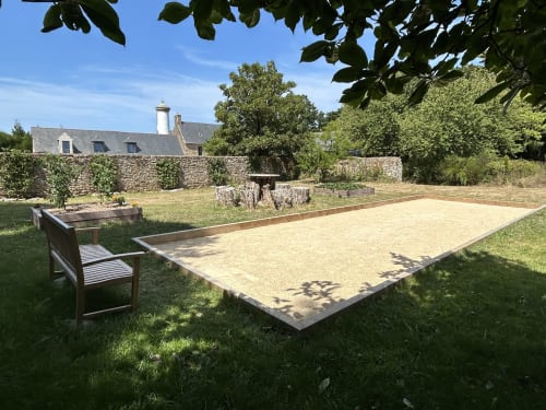 Terrain de pétanque et banc à Sous Le Phare B&B à Louannec, France avec bâtiments en pierre et jardins