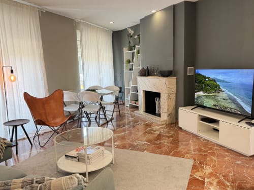 Sala de estar moderna en Stay Gest Valencia con sillón de cuero, chimenea, TV y suelos de mármol