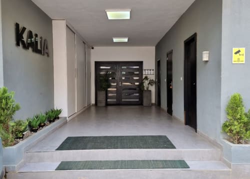 Entrada moderna del hotel DakarByDays con puertas de vidrio, plantas en macetas y pasillo acogedor en Dakar