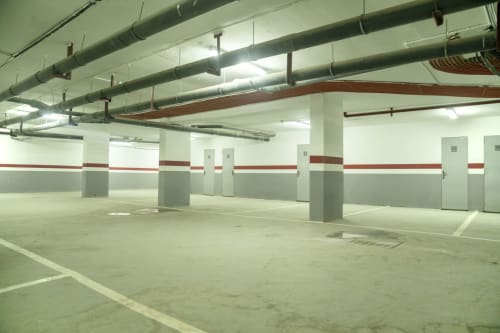 Garaje subterráneo vacío del hotel DakarByDays en Dakar con pilares de hormigón e iluminación fluorescente.