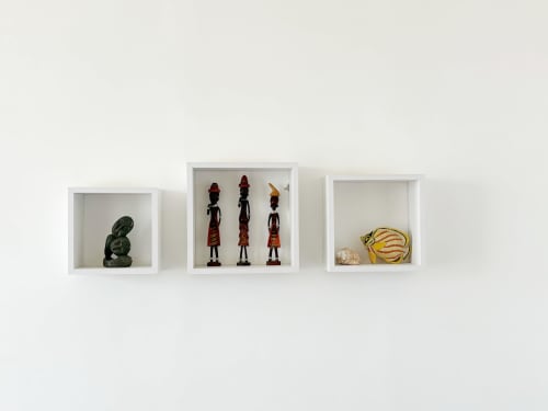 Tres estantes blancos de pared que exhiben arte y esculturas africanas en el hotel DakarByDays en Dakar