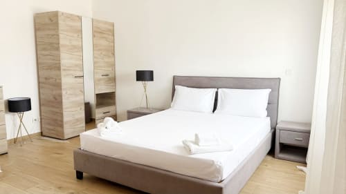 Modern bedroom at DakarByDays apartment in Dakar with gray upholstered bed, wooden wardrobe, and wood flooring
