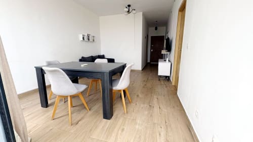 Modern dining area in DBD901 Appartement ERIKA, Dakar with dark table, white chairs, and wooden floors