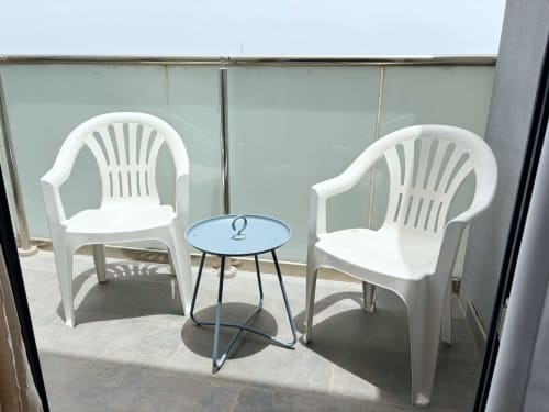 Balcony seating area at DakarByDays apartment with two white chairs and small blue table overlooking Dakar city view