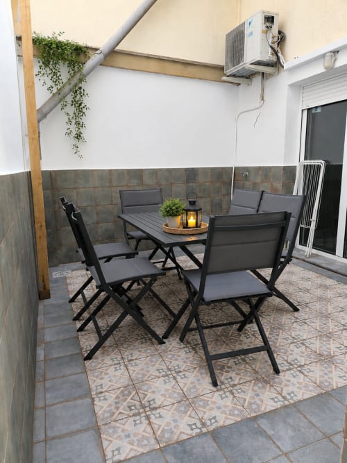 Modern patio at Principe David apartment in Toledo with black furniture, tiled flooring, and air conditioning unit