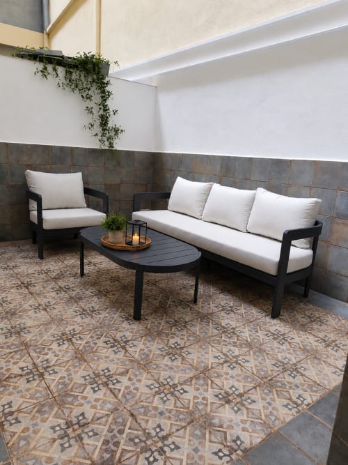 Modern patio seating area at Principe David Toledo apartment with black furniture, white cushions, patterned tile floor, and