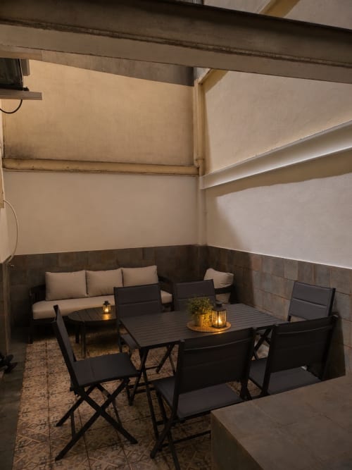 Cozy outdoor terrace at Principe David in Toledo with black furniture, cushioned seating, lanterns, and neutral walls