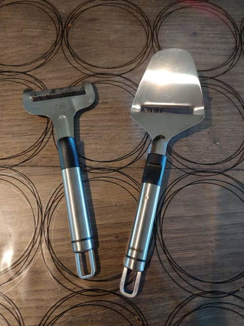 Deux outils de jardinage aux manches bleus sur un tapis à motifs au Jardin de la Reyssouze, chambres d'hôtes à Gorrevod