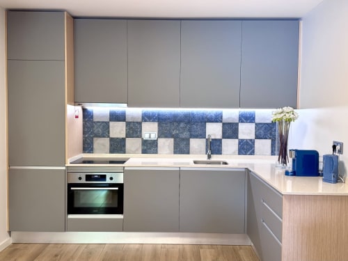 Cuisine moderne avec carrelage damier bleu et blanc, armoires grises et appareils inox à l'hôtel RIA CENTRUM