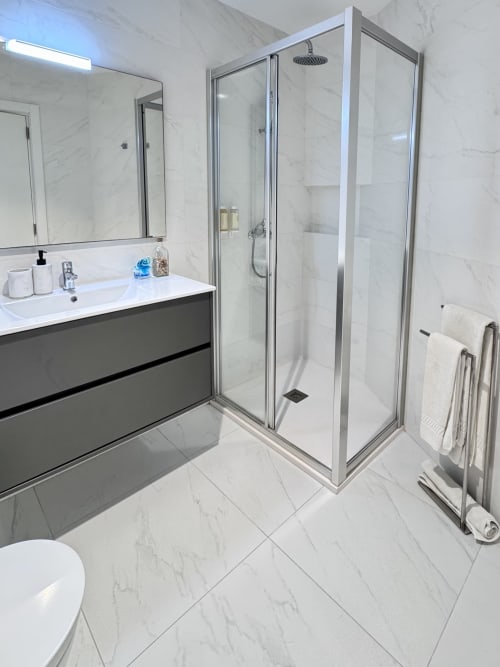 Salle de bain moderne au RIA CENTRUM Aveiro avec carrelage en marbre, lavabo meuble-vasque, cabine de douche vitrée et sèche-serviettes chauffant