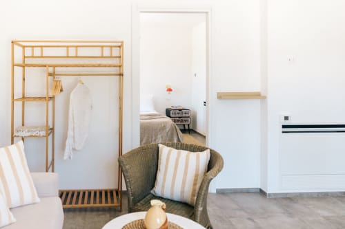 Modern apartment bedroom at Tenuta Fascianello, Fasano, with wooden wardrobe, striped cushions, and wicker chair