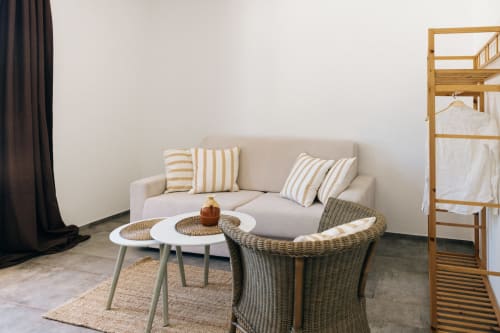 Modern apartment living area at Tenuta Fascianello with beige sofa, striped pillows, wicker chair, and wooden bunk bed