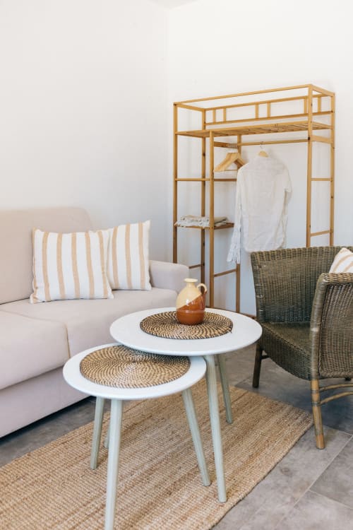 Stylish apartment seating area at Tenuta Fascianello with striped cushions, wicker chairs, wooden wardrobe, and round tables