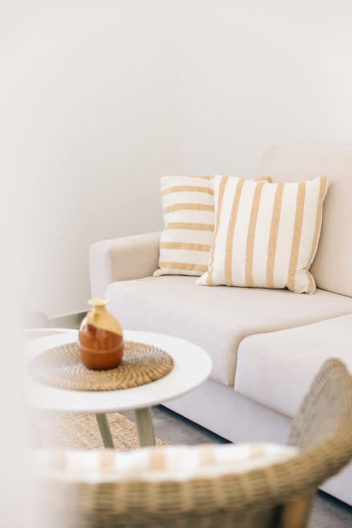 Elegant living room at Tenuta Fascianello with cream sofa, striped pillows, and round white side table with golden decor