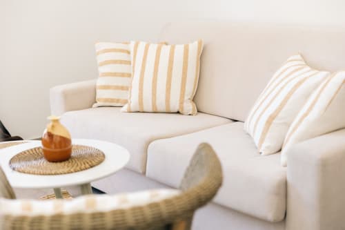 Cream and beige striped pillows on white seating at Tenuta Fascianello apartment in Fasano, Italy