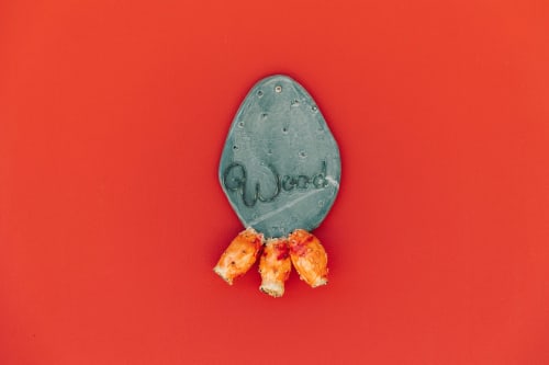 Decorative metal egg ornament with 'Good' text and coral flowers against red background at Tenuta Fascianello, Fasano