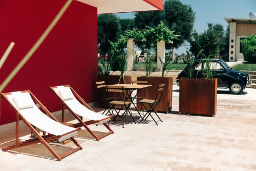 Outdoor terrace at Tenuta Fascianello with lounge chairs, dining table, and red shade structure overlooking gardens in