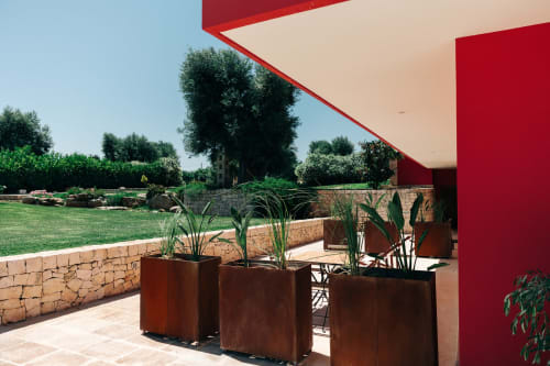 Modern red building terrace with planters overlooking green gardens at Tenuta Fascianello, Fasano Italy
