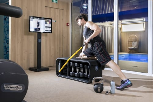 Homme utilisant des cordes d'entraînement dans la salle de fitness moderne de l'Hôtel Résidence Europe & Spa, Clichy