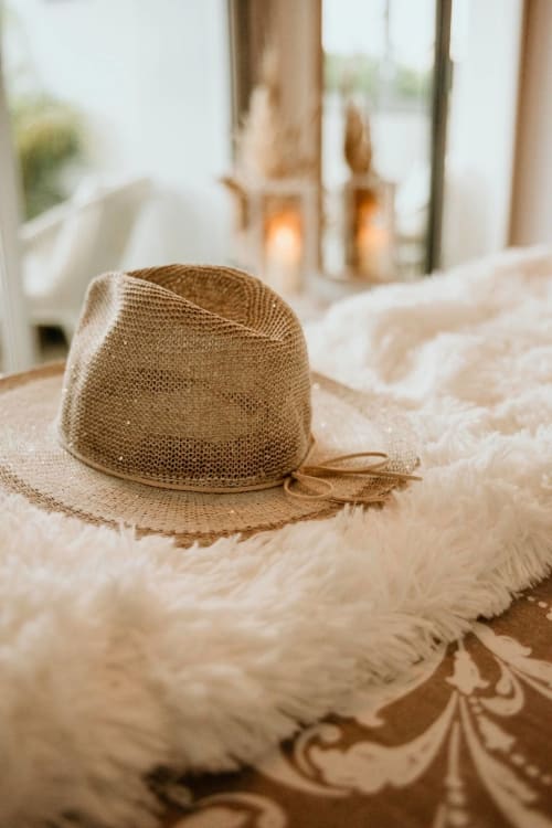 Straw hat on bed at Sable & Pampas boutique hotel in Carnon-Plage, France