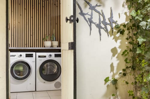 Modern laundry room at Hotel Residence Europe & Spa with washer, dryer, and potted plants in Clichy