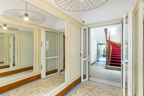 Hotel Residence Europe & Spa entrance hallway with mirrored walls, pendant lights, and red staircase in Clichy