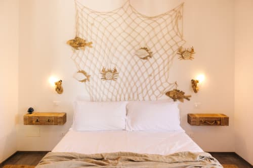 Coastal-themed bedroom at Tenuta Fascianello with fishing net, golden sea creatures, white bed, and vintage suitcase