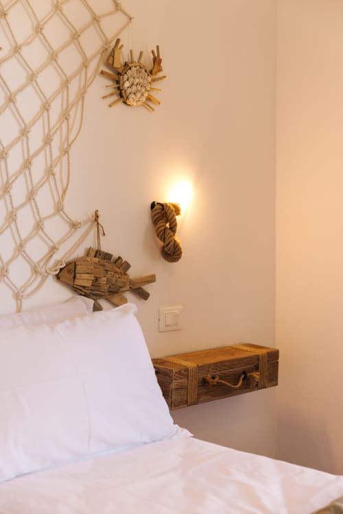 Coastal bedroom at Tenuta Fascianello with nautical decor: rope knot, wooden fish sculpture, and sunlit wall in Fasano.