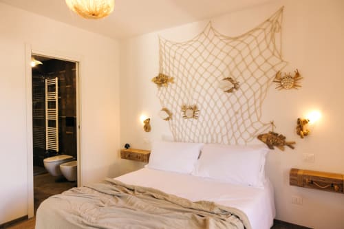 Cozy bedroom at Tenuta Fascianello with nautical decor, fishing net headboard, golden sea creatures, and ensuite bathroom in