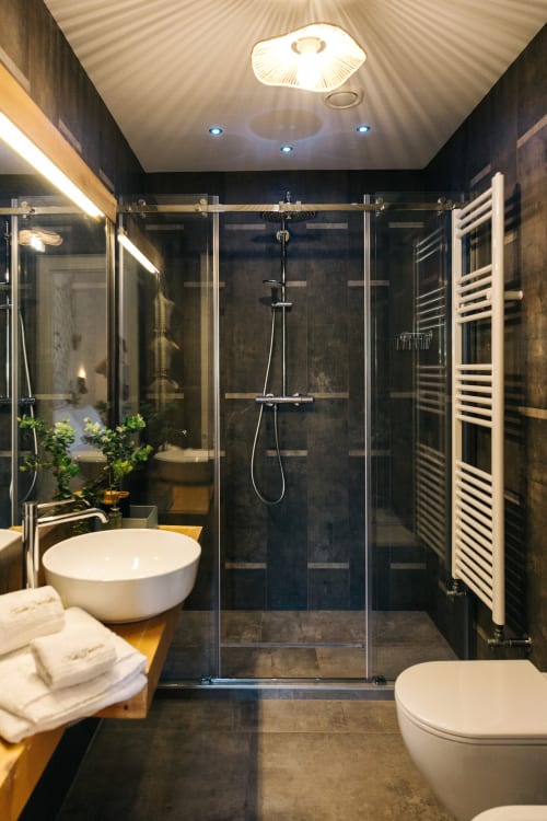 Modern bathroom with rainfall shower, round sink, heated towel rack, and dark tiled walls at Tenuta Fascianello in Fasano