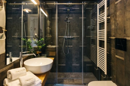 Modern bathroom at Tenuta Fascianello with white vessel sink, walk-in shower, dark tile walls, and heated towel rack