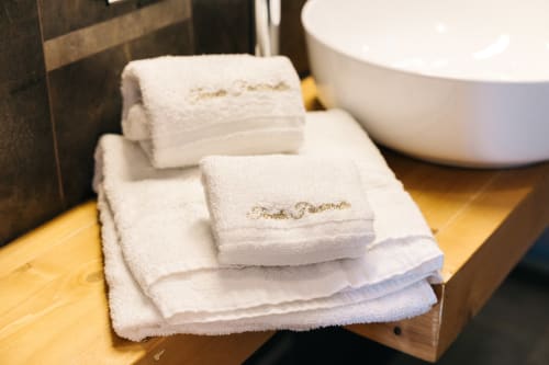 Rolled white towels with gold embroidery at Tenuta Fascianello hotel in Fasano, Italy bathroom