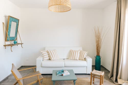 Bright modern living room at Tenuta Fascianello with white sofa, striped cushions, wooden furniture, and teal accents