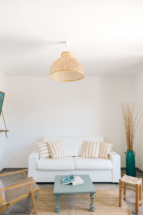 Modern living room in Fasano apartment with white sofa, woven pendant light, and garden views