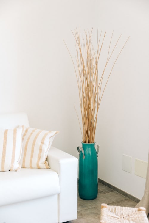 Tenuta Fascianello apartment in Fasano with white sofa, striped pillow, and teal vase with dried grass decor