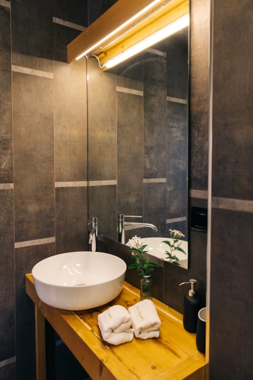 Bagno moderno nella Jungle room di Tenuta Fascianello, Fasano, con lavabo bianco, mobile giallo e pareti rivestite in scuro