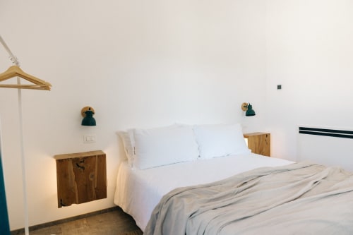 Camera minimalista a Tenuta Fascianello con biancheria bianca, comodini in legno, lampade verdi e vista giardino a Fasano.
