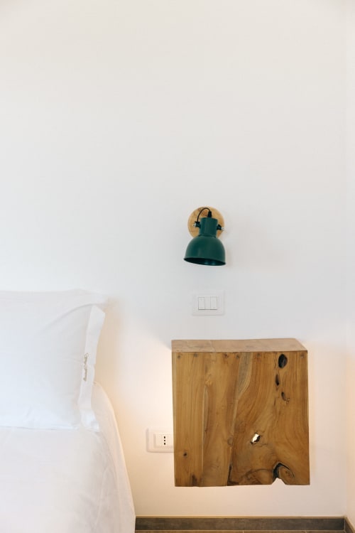 Angolo minimalista della camera da letto presso Tenuta Fascianello con applique teal e dettaglio di mobile in legno